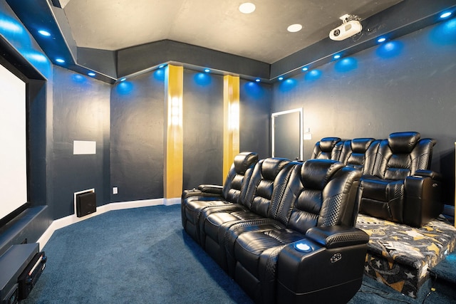 carpeted home theater room with vaulted ceiling and baseboards