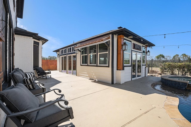 view of patio / terrace featuring a pool with connected hot tub and a fenced backyard