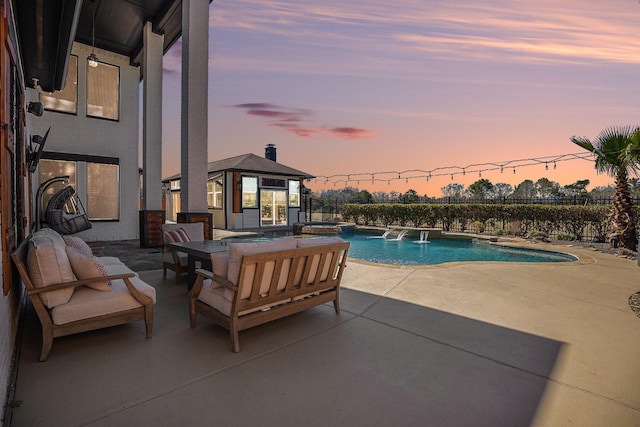 pool at dusk featuring an outbuilding, fence, a pool with connected hot tub, outdoor lounge area, and a patio area