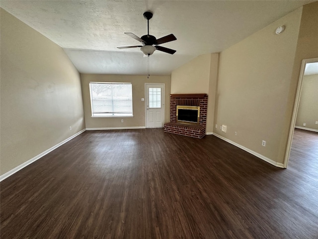 unfurnished living room featuring a ceiling fan, baseboards, lofted ceiling, dark wood-style flooring, and a brick fireplace