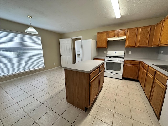 kitchen featuring under cabinet range hood, white appliances, brown cabinetry, and light tile patterned floors