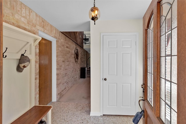 mudroom featuring brick wall and speckled floor