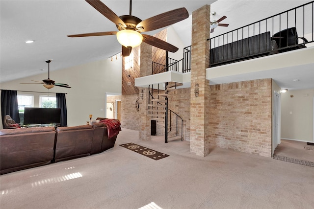 carpeted living room with brick wall, stairway, and a towering ceiling