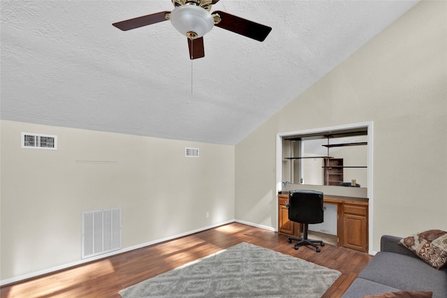 office area featuring vaulted ceiling, dark wood-type flooring, and visible vents