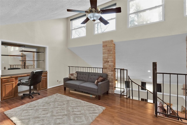 office space featuring a towering ceiling, a textured ceiling, baseboards, and wood finished floors