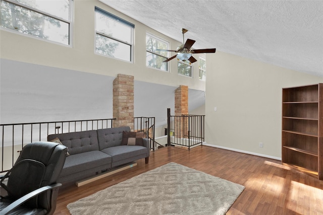 living area with a textured ceiling, wood finished floors, and decorative columns