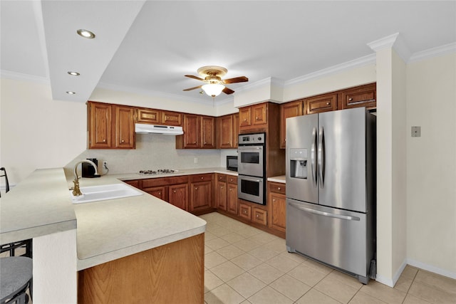 kitchen with light countertops, appliances with stainless steel finishes, a sink, a peninsula, and under cabinet range hood