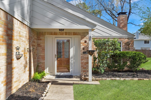 property entrance featuring brick siding and a chimney