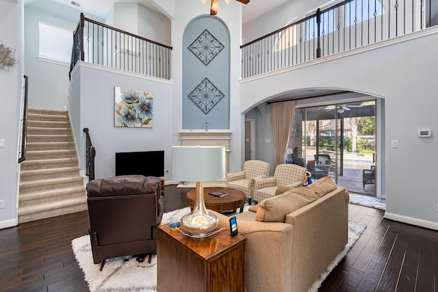 living room with arched walkways, wood-type flooring, ceiling fan, and baseboards