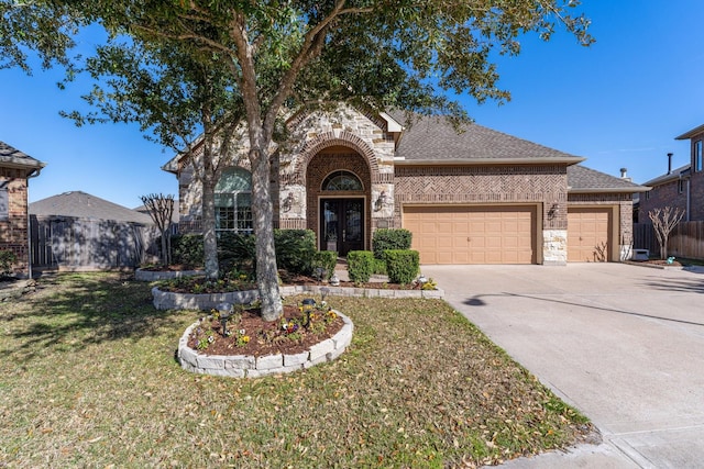 view of front of property with french doors, brick siding, an attached garage, fence, and driveway