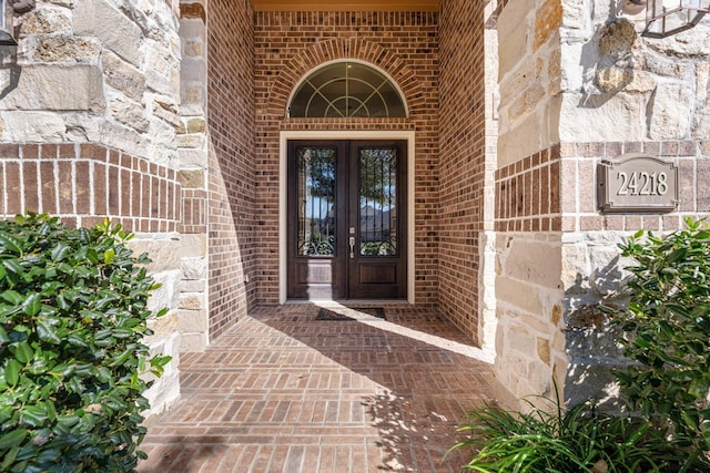 view of exterior entry with french doors and brick siding