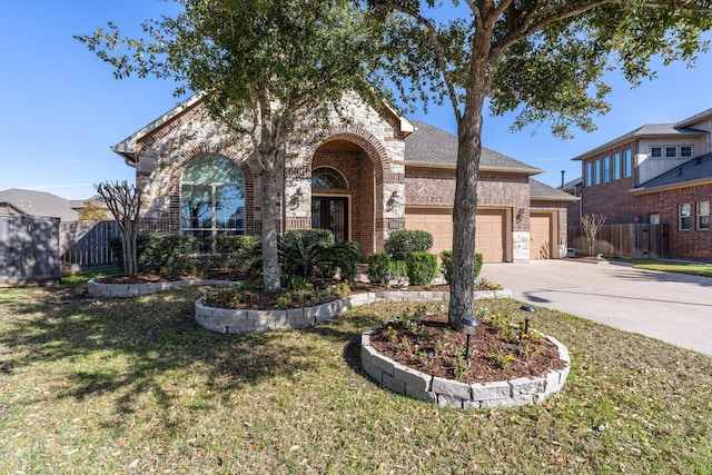 view of front of home with driveway, brick siding, an attached garage, fence, and a front yard