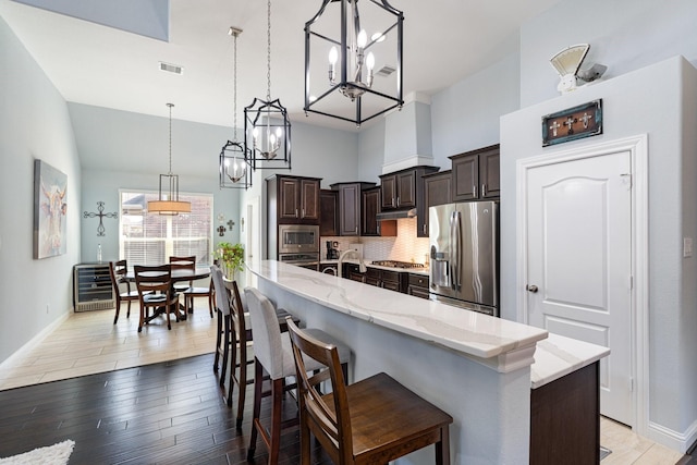 kitchen featuring visible vents, backsplash, appliances with stainless steel finishes, dark brown cabinetry, and beverage cooler