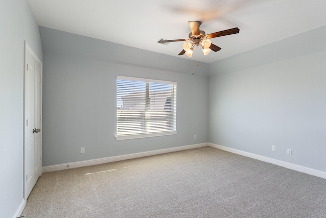 carpeted spare room featuring ceiling fan and baseboards