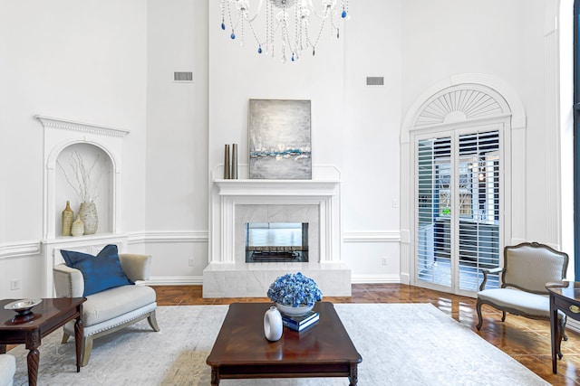 living room with visible vents, baseboards, a towering ceiling, and a premium fireplace