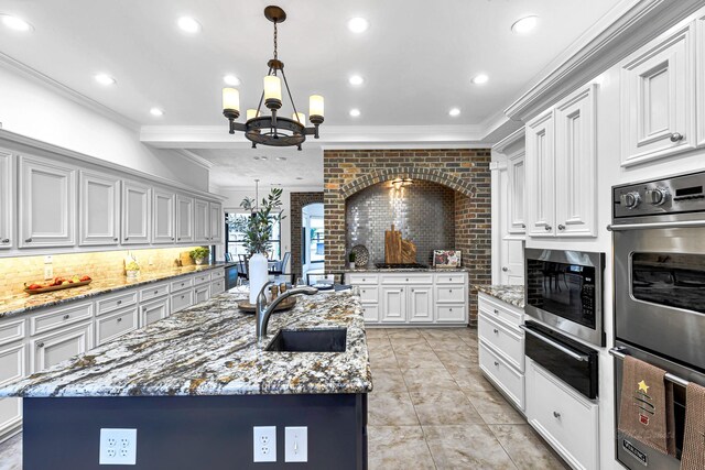 kitchen featuring a sink, stainless steel appliances, crown molding, a warming drawer, and a chandelier