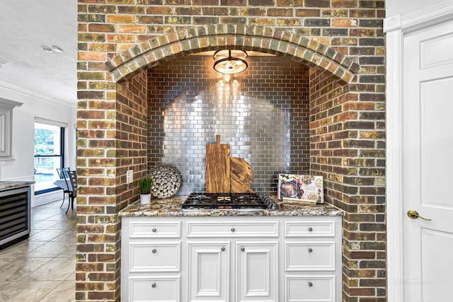 kitchen featuring light tile patterned floors, light stone counters, backsplash, and stainless steel gas stovetop