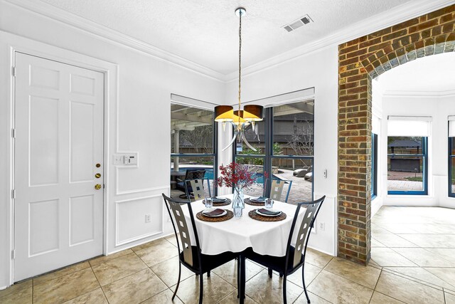 dining area with arched walkways, visible vents, a textured ceiling, and ornamental molding