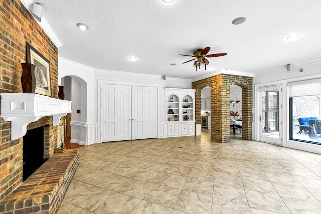 unfurnished living room with arched walkways, ornamental molding, and a fireplace