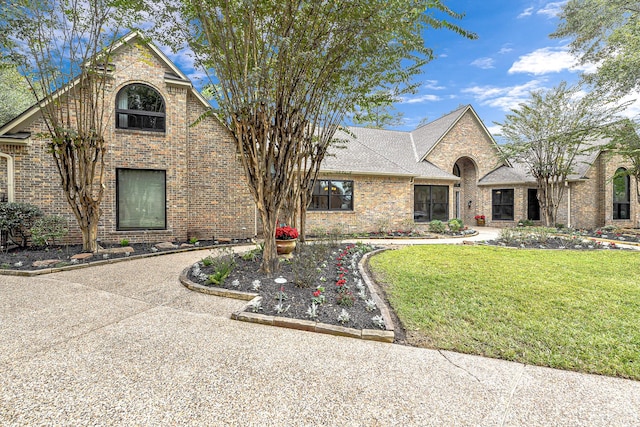 view of front facade with a front lawn, brick siding, and a shingled roof