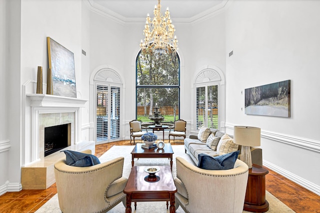 living area with a notable chandelier, a high ceiling, crown molding, baseboards, and a tile fireplace