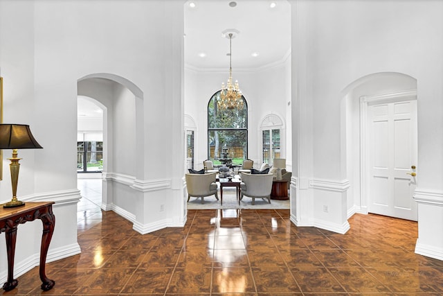 tiled entrance foyer with crown molding, baseboards, a high ceiling, an inviting chandelier, and arched walkways