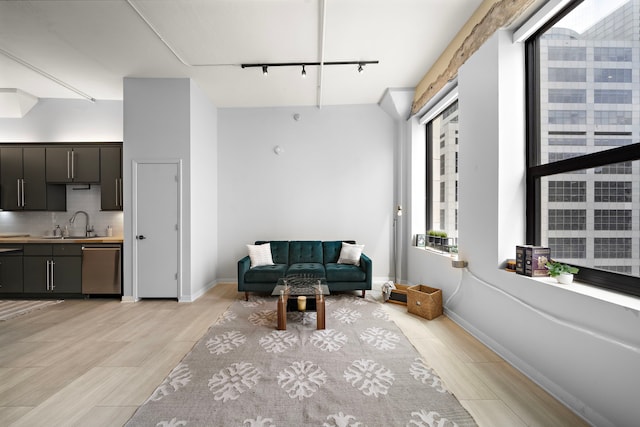 interior space featuring track lighting, vaulted ceiling, baseboards, and wood finish floors