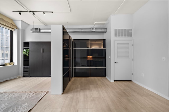 spare room with visible vents, rail lighting, and baseboards