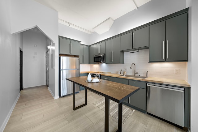 kitchen featuring a sink, stainless steel appliances, baseboards, and backsplash