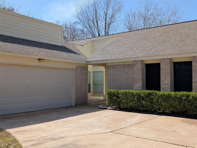 exterior space with brick siding, driveway, and a shingled roof