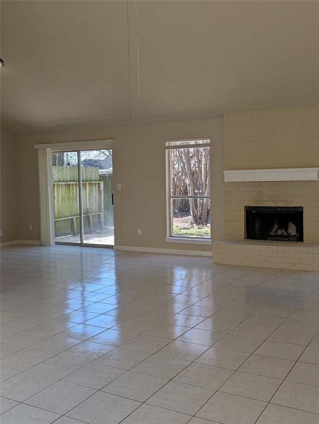 unfurnished living room with light tile patterned floors, baseboards, plenty of natural light, and a fireplace