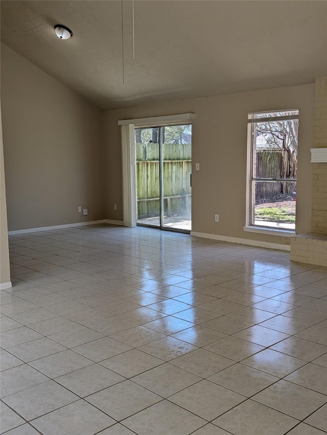 unfurnished room with lofted ceiling, light tile patterned floors, and baseboards