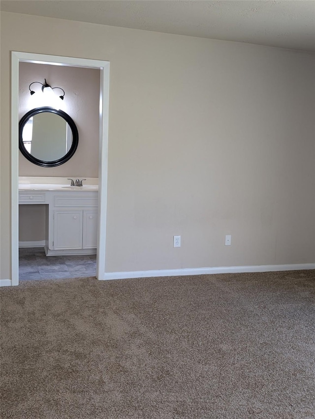 unfurnished room with light carpet, baseboards, and a sink