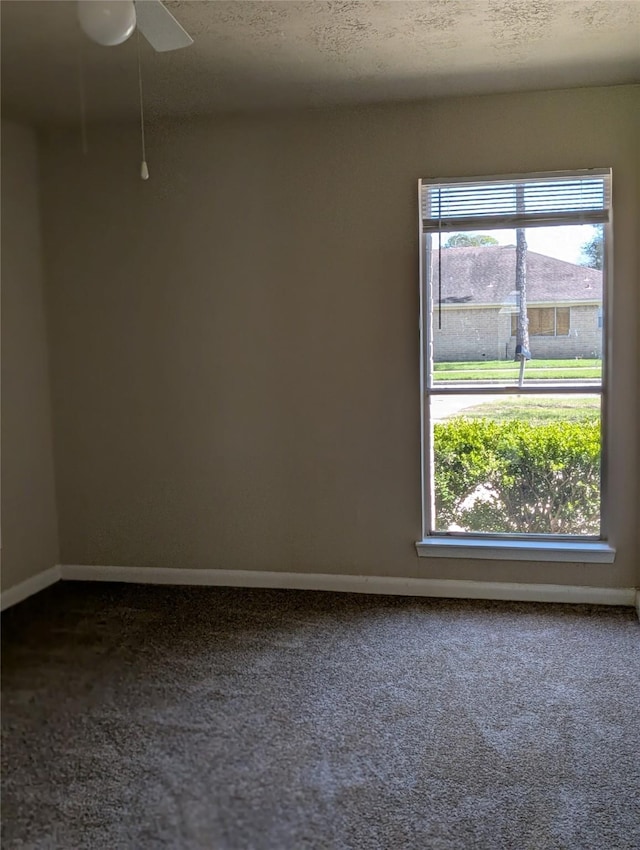 carpeted empty room featuring a textured ceiling, baseboards, and a ceiling fan