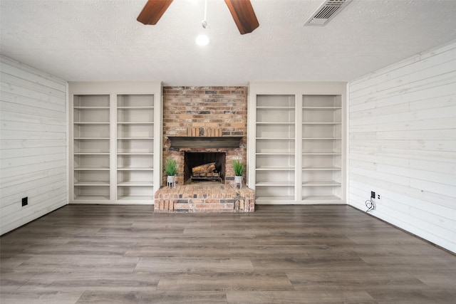 unfurnished living room featuring wood finished floors, a fireplace, visible vents, and a textured ceiling