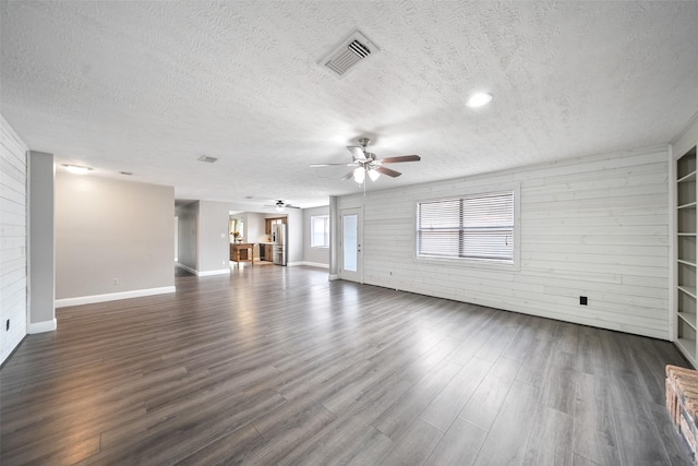 unfurnished living room with a ceiling fan, dark wood-style floors, visible vents, and a textured ceiling