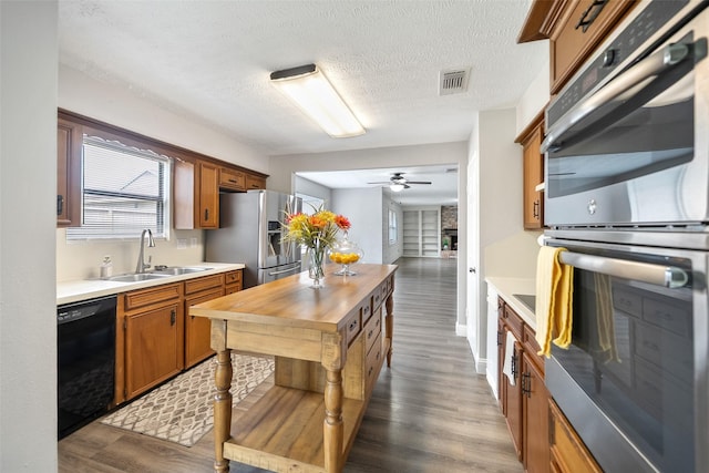 kitchen featuring visible vents, a sink, dark wood finished floors, stainless steel appliances, and wooden counters