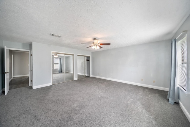 unfurnished bedroom with visible vents, multiple windows, two closets, and carpet