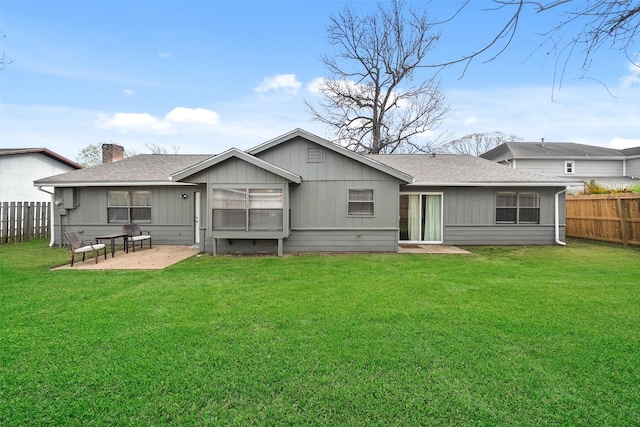 rear view of house with fence, roof with shingles, a chimney, a patio area, and a lawn