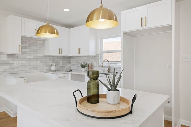 kitchen featuring light stone countertops, tasteful backsplash, and white cabinets