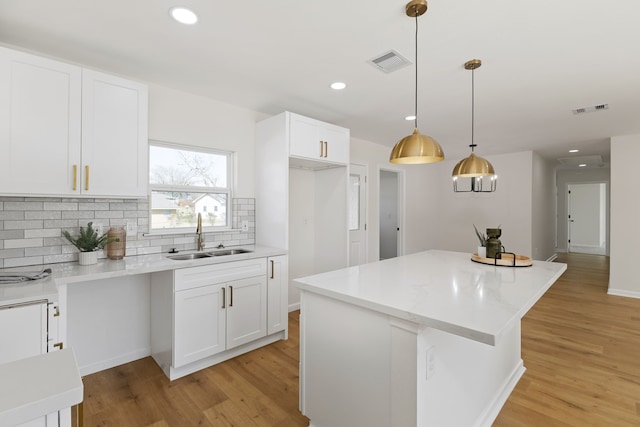 kitchen with light wood-style flooring, visible vents, and a sink