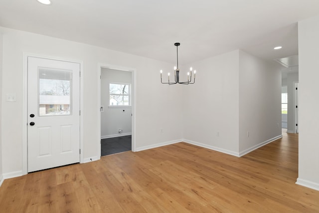 unfurnished dining area with recessed lighting, baseboards, a notable chandelier, and light wood-style flooring