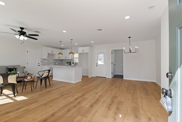 kitchen with visible vents, backsplash, open floor plan, light countertops, and white cabinets