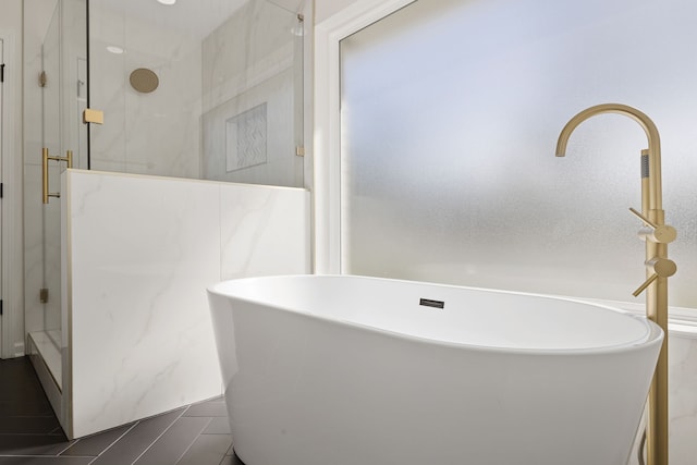 bathroom with a marble finish shower and a freestanding bath