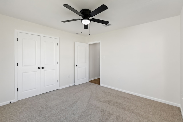 unfurnished bedroom featuring visible vents, a closet, carpet flooring, baseboards, and ceiling fan