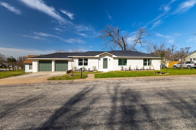 ranch-style home with a garage, concrete driveway, a front yard, and stucco siding