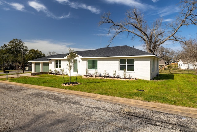 view of front of property featuring concrete driveway, a front yard, a shingled roof, a garage, and brick siding