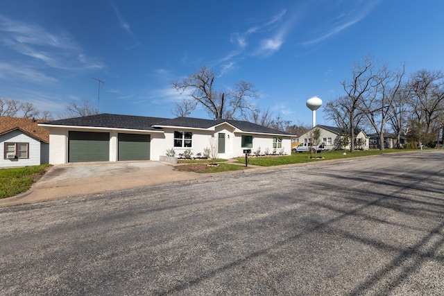 ranch-style home with a garage, driveway, and stucco siding