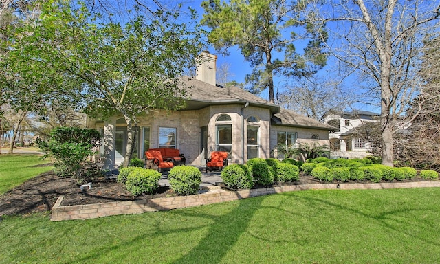 rear view of house featuring brick siding, a lawn, a chimney, and a patio