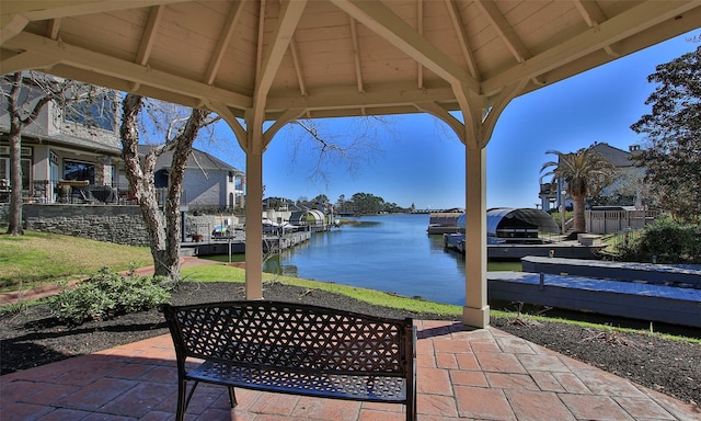 view of patio with a gazebo, a water view, and a dock